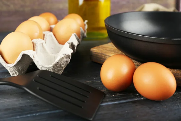 Still life with eggs and pan on wooden background — Stock Photo, Image