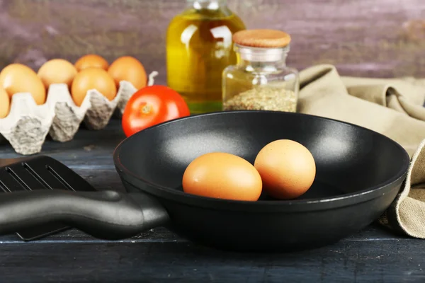 Bodegón con huevos y sartén sobre fondo de madera —  Fotos de Stock