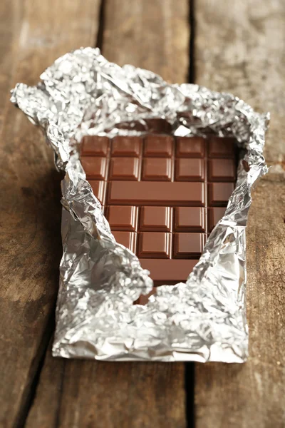 Çikolata folyo ahşap arka plan üzerinde — Stok fotoğraf
