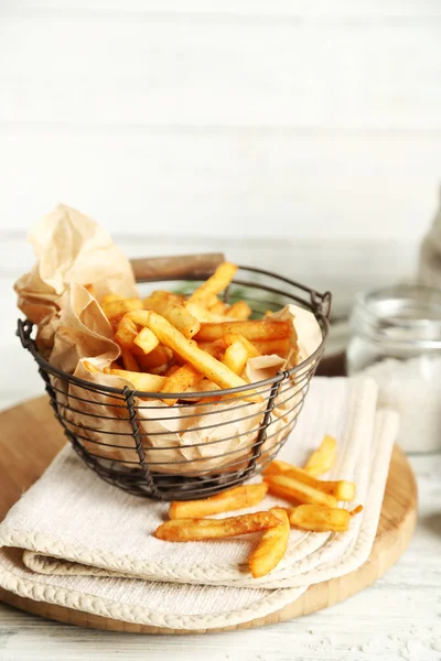 Smakelijke Franse frietjes in metalen mand op een houten achtergrond kleur — Stockfoto