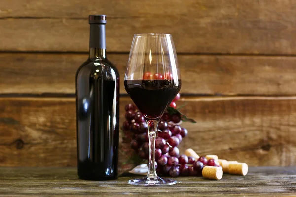 Bottle and glass of wine with grape on wooden background — Stock Photo, Image