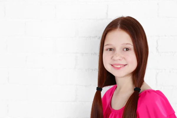 Menina bonita em tijolos parede fundo — Fotografia de Stock