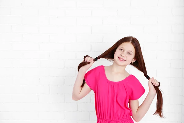 Beautiful little girl on bricks wall background — Stock Photo, Image