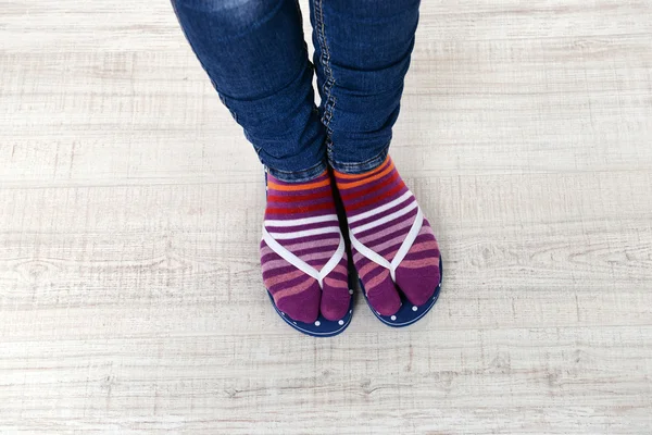 Female feet in socks with pink flip-flops, on floor background — Stock Photo, Image