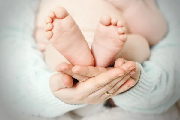 Newborn baby feet on female hands, close-up — Stock Photo, Image