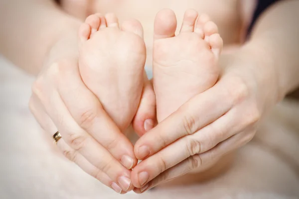 Pies de bebé recién nacidos en manos femeninas, primer plano — Foto de Stock