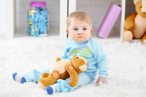 Schattige babyjongen met teddy bear op tapijt, op lichte achtergrond — Stockfoto