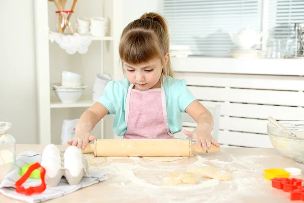 Lille pige forbereder cookies i køkkenet derhjemme - Stock-foto