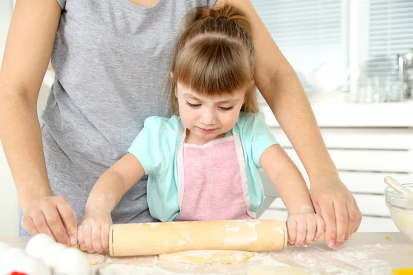 Маленькая девочка готовит печенье с мамой на кухне дома — стоковое фото