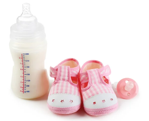 Baby shoes with nipple and bottle of milk isolated on white — Stock Photo, Image