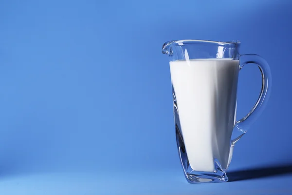 Jarro de leite no fundo azul — Fotografia de Stock