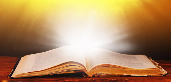 Открытая книга на столе на коричневом фоне
