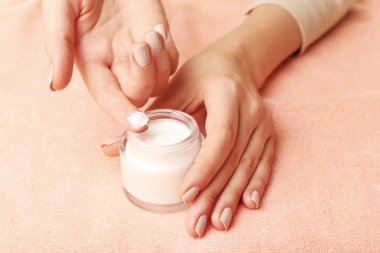 Kumaş arka plan üzerinde krema kavanozu ile eller