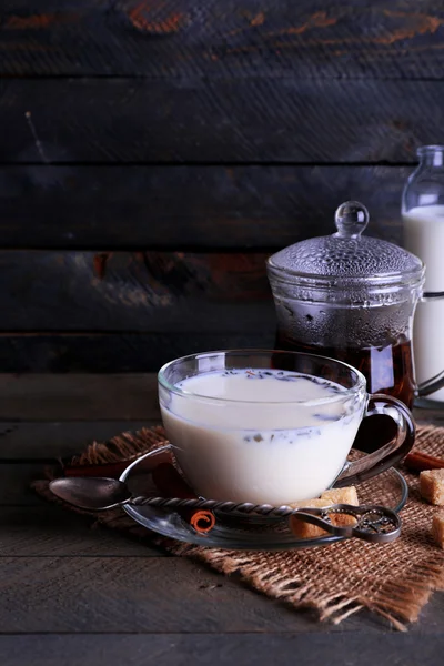 Černý čaj s mlékem v sklo a kusový cukr na barvu pozadí Dřevěná prkna — Stock fotografie