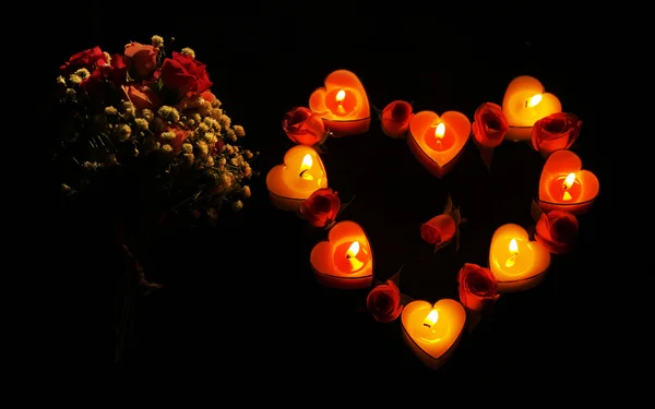 Atmosfera romântica com luzes de vela e flores no fundo escuro — Fotografia de Stock