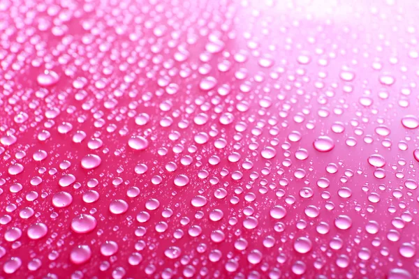 Gotas de agua sobre vidrio sobre fondo rosa — Foto de Stock