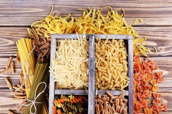 Diferentes tipos de pasta en caja sobre fondo de madera —  Fotos de Stock