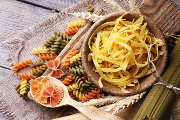 Diversi tipi di pasta su sacco su fondo di legno — Foto Stock