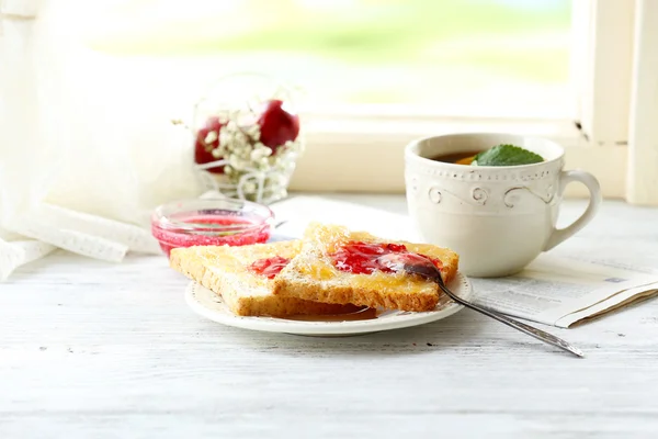 Rostat bröd med sylt på plattan och kopp te på ljus bakgrund — Stockfoto