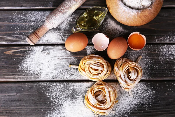 Pasta mentah buatan sendiri dan bahan-bahan untuk pasta pada latar belakang kayu — Stok Foto