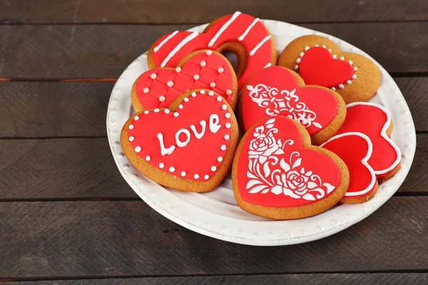 Galletas en forma de corazón para San Valentín en plato, sobre fondo de madera —  Fotos de Stock