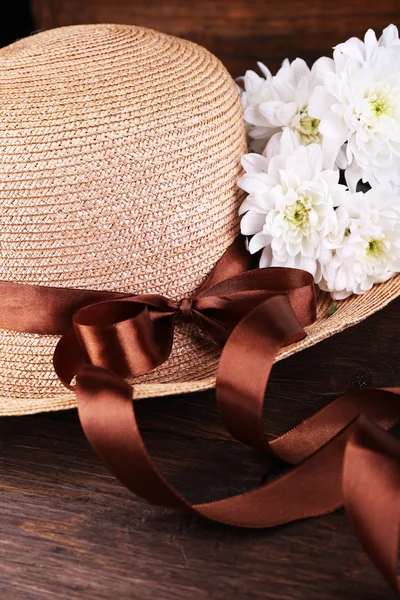 Hat with flowers on wooden background, closeup — Stock Photo, Image