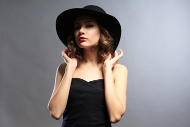 Siyah elbise ve şapka gri arka plan üzerinde güzel model portresi