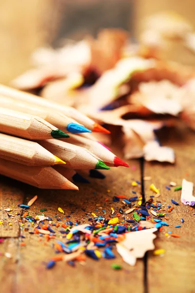 Wooden colorful pencils with sharpening shavings, on wooden table — Stock Photo, Image