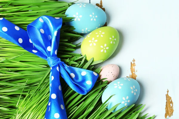 Easter eggs and grass on wooden background — Stock Photo, Image