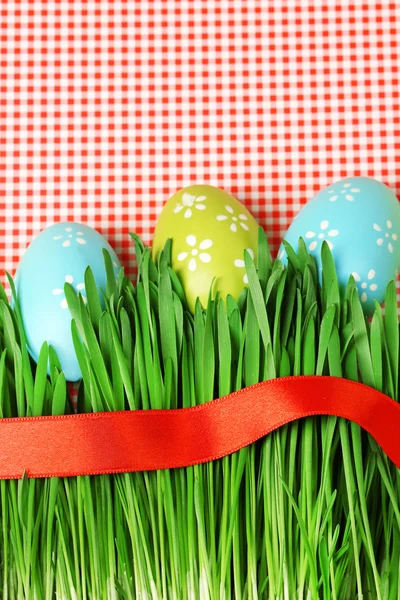 Paskalya yumurtaları ve renkli kağıt arka plan üzerinde çim — Stok fotoğraf
