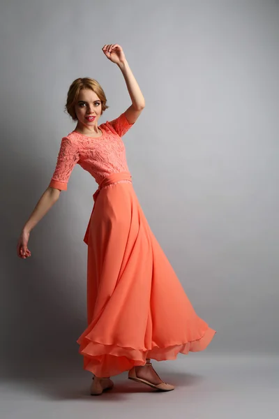 Beautiful young woman in color dress posing on light background — Stock Photo, Image