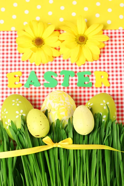 Пасхальные яйца и трава на цветном бумажном фоне — стоковое фото