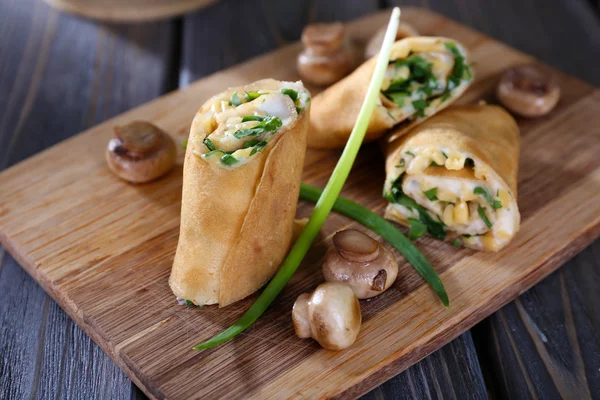 Pfannkuchen mit cremigen Pilzen auf Schneidebrett auf Holztisch, Nahaufnahme — Stockfoto