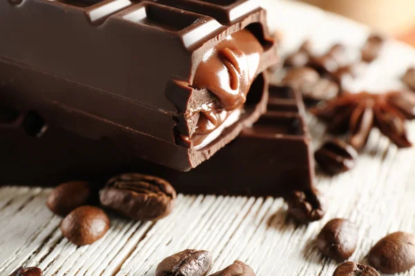 Gefüllte Schokolade mit Kaffeebohnen auf Holztisch, Nahaufnahme — Stockfoto