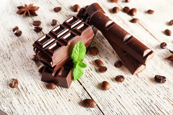 Gefüllte Schokolade mit Kaffeebohnen und Minze auf Holzgrund — Stockfoto