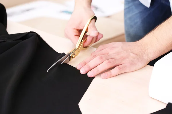 Pria pembuat gaun memotong kain di meja close-up — Stok Foto
