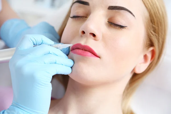 Kosmetolog tillämpa permanent göra upp läpparna — Stockfoto