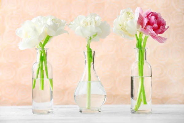 Beautiful tulips in glass vases on light color background — Stock Photo, Image