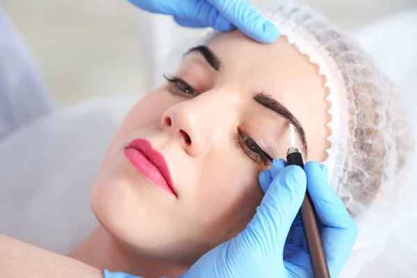 Cosmetólogo aplicando maquillaje permanente en las cejas —  Fotos de Stock