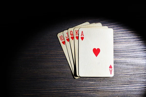 Playing cards in light on wooden table, top view — Stock Photo, Image