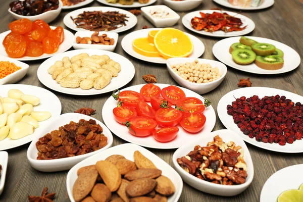 Different products on saucers on wooden table, closeup — Stock Photo, Image