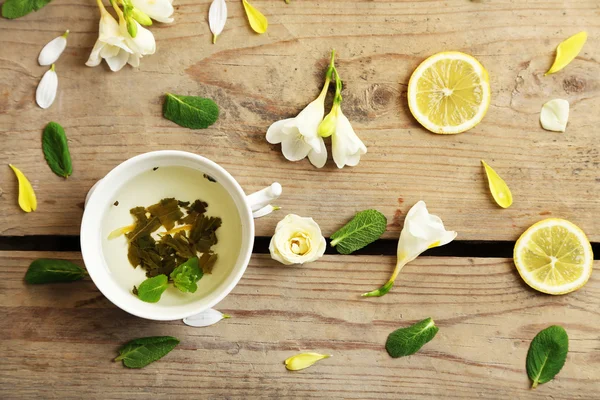 Tazza di tisana con bellissimi fiori, su sfondo di legno — Foto Stock