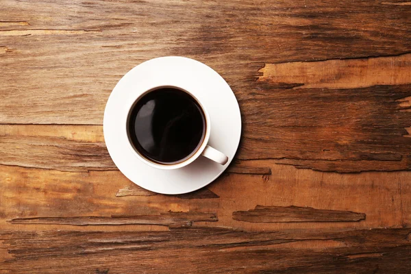 Bir fincan kahve, ahşap masa, üst manzara.