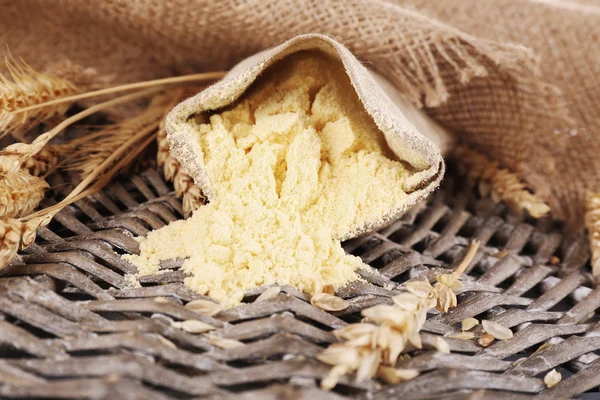 Farinha inteira em saco com espigas de trigo no tapete de vime, close-up — Fotografia de Stock