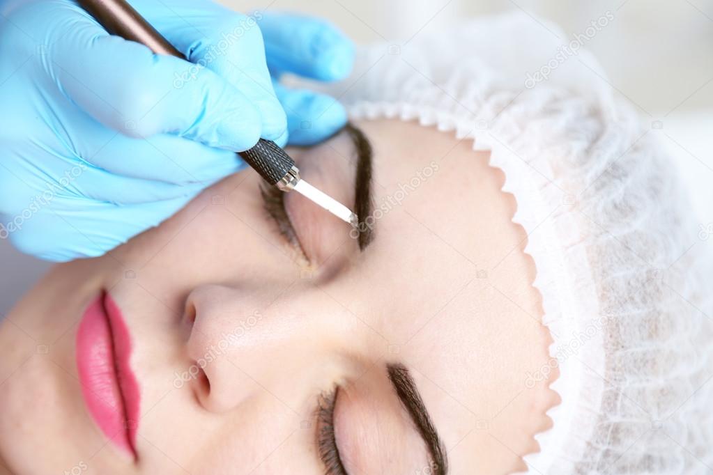Cosmetologist applying permanent make up on eyebrows