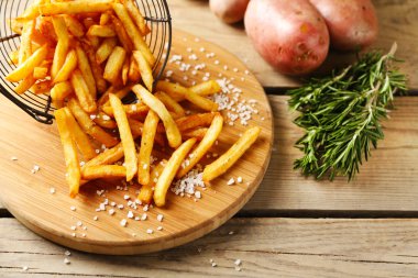 Ahşap masa arkasında metal sepetin içinde patates kızartması.