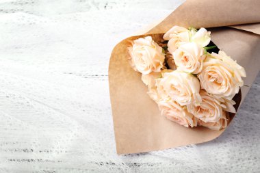 Kağıt ahşap arka plan üzerinde sarılı taze gül buketi