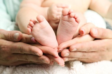Yeni doğan bebeğin ayakları üzerinde baba ve anne eller, yakın çekim