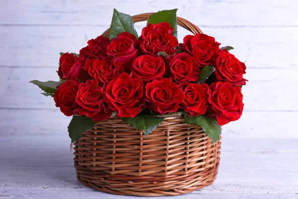 Bouquet of red roses in basket on wooden background — Stock Photo, Image