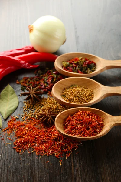 Different kinds of spices in spoons, close-up, on wooden background — Stock Photo, Image